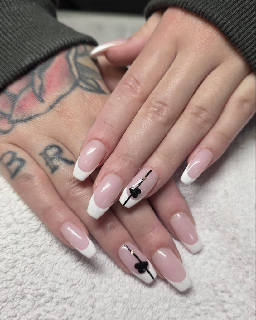 Square nails in a pale pink with white French tips, two of them finished with a small black bow