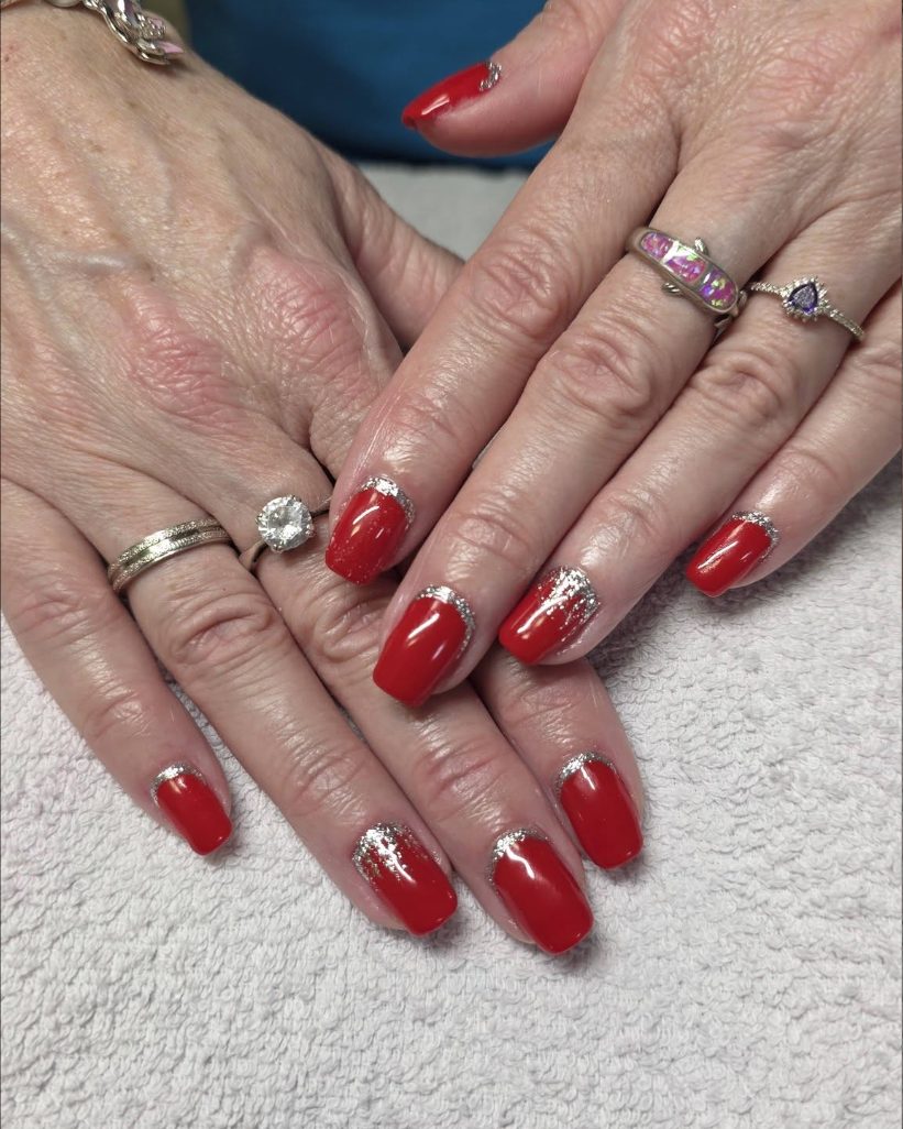 Short red nails with a band of silver glitter swept along the base of each one
